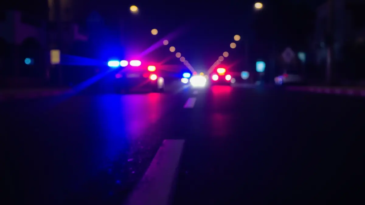 Imatge genèrica de llums d'emergència reflectint-se sobre l'asfalt mullat de nit.