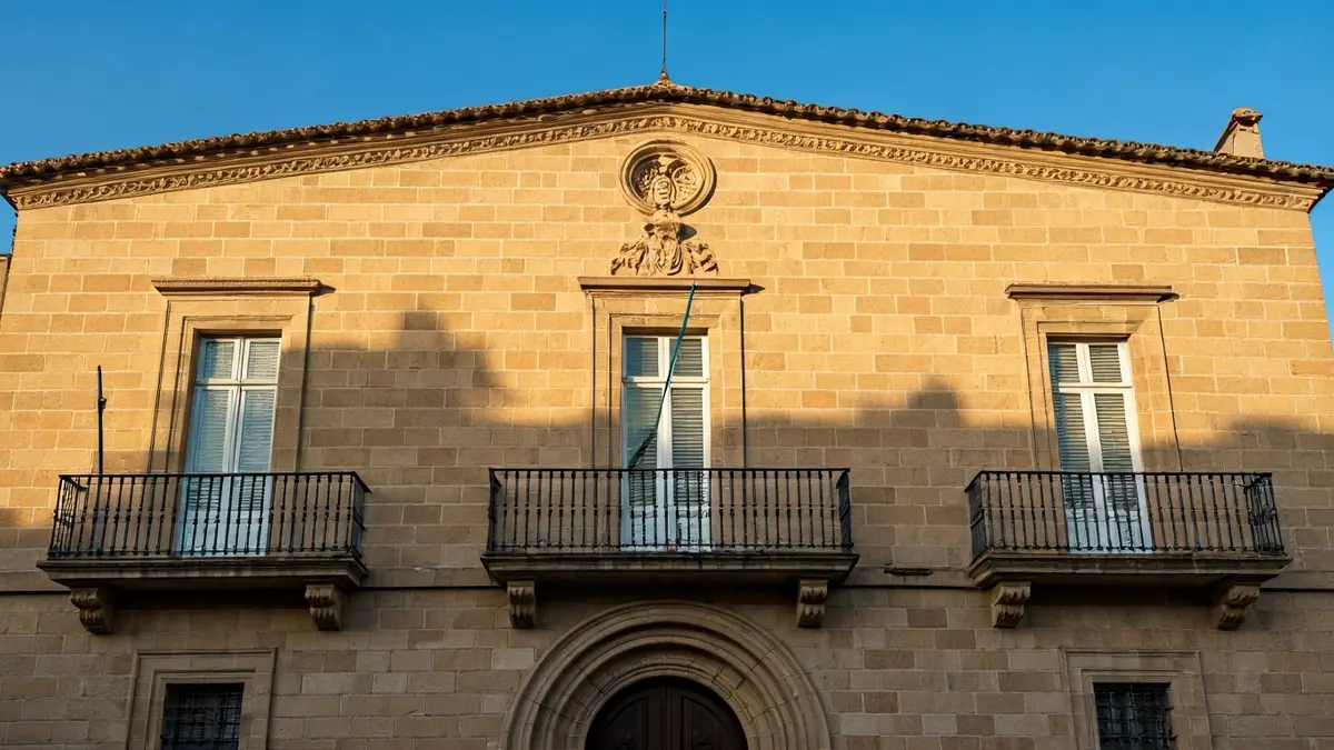 Façana de l'Ajuntament de Valls amb balcó de ferro forjat sota la llum del sol.