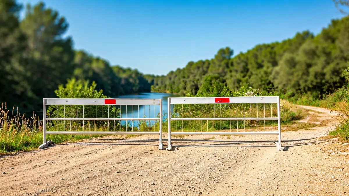Imatge d'una barrera que impedeix el pas en un camí prop d'una zona natural.