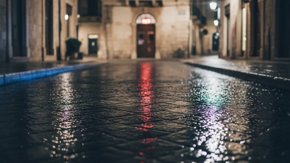 Imatge genèrica de llums d'emergència reflectint-se sobre asfalt mullat en un entorn urbà mediterrani.