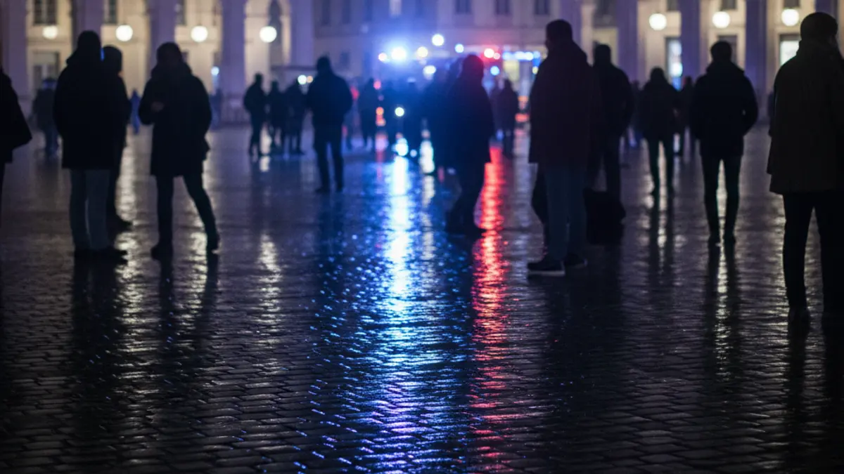 Generic image of emergency lights reflecting on wet asphalt in a city square at night.