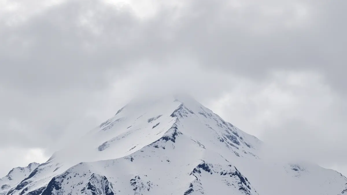 Image of a snow-covered peak in the Pyrenees under a stormy sky, evoking the Balandrau tragedy.