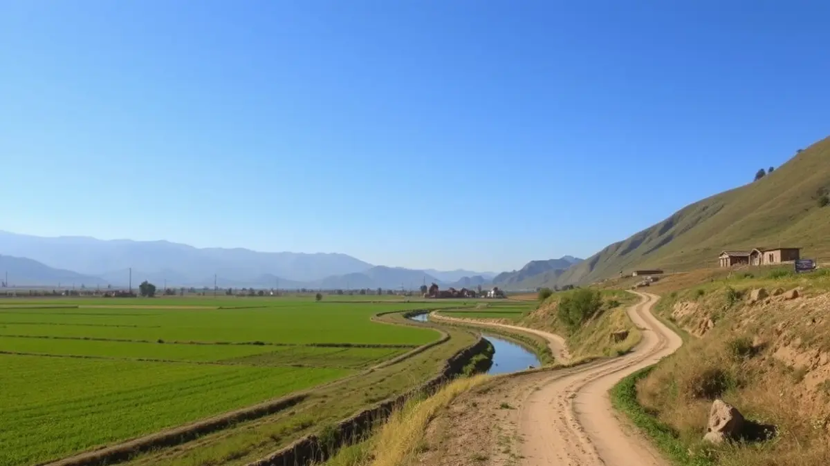 Imatge d'un camí al costat d'una séquia, amb camps verds i muntanyes al fons.