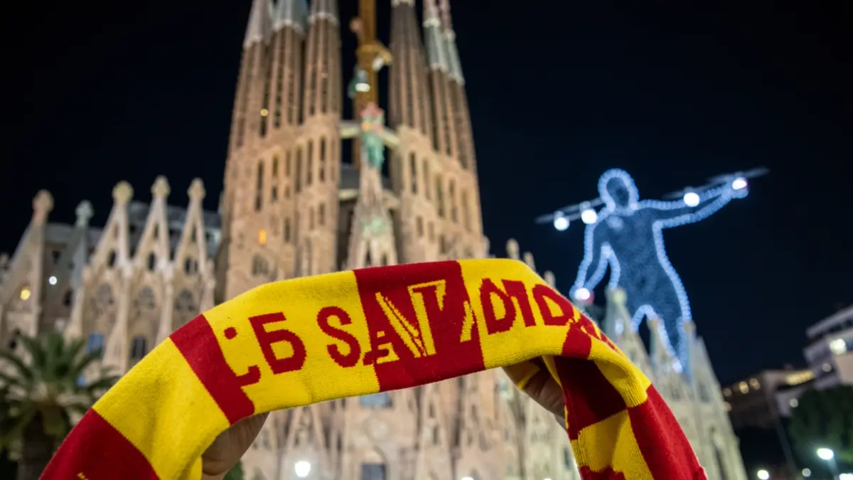 UE Sant Andreu club scarf gifted to Pope Leo XIV in front of the illuminated Sagrada Familia.