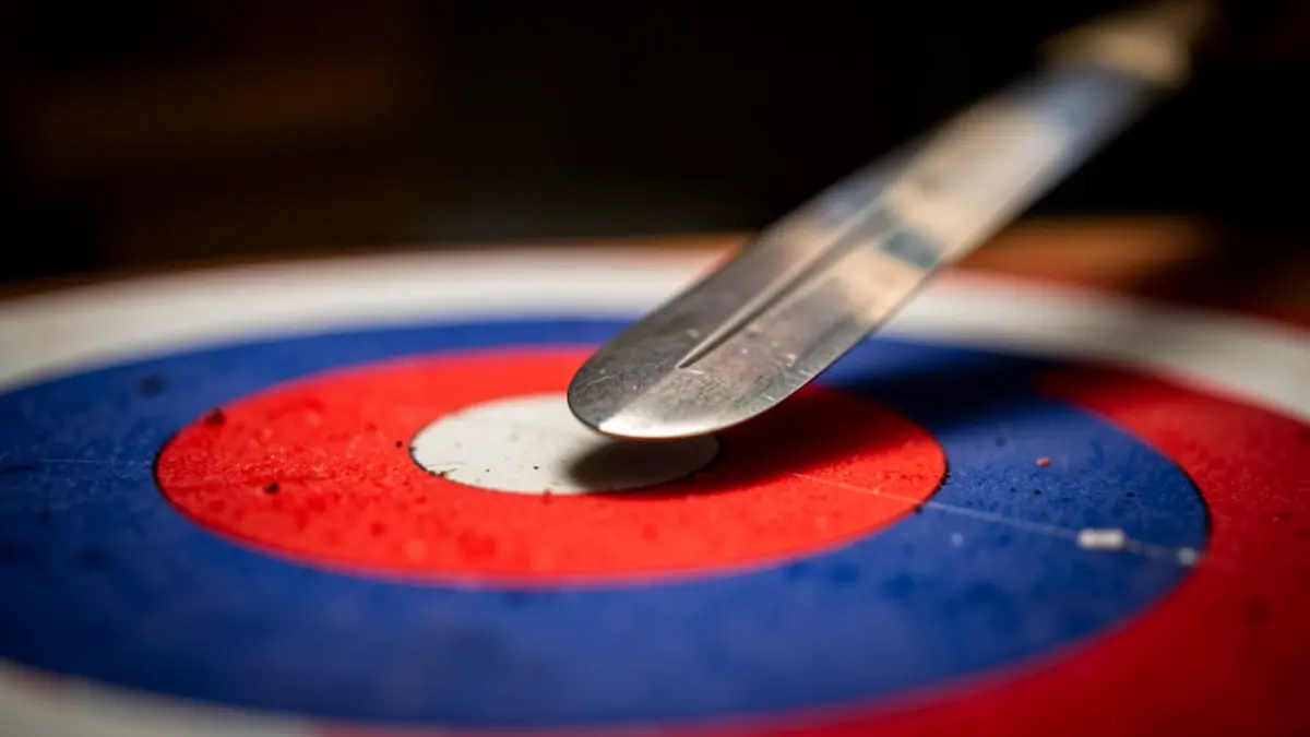 Tip of a fencing foil sword on a red and blue target.