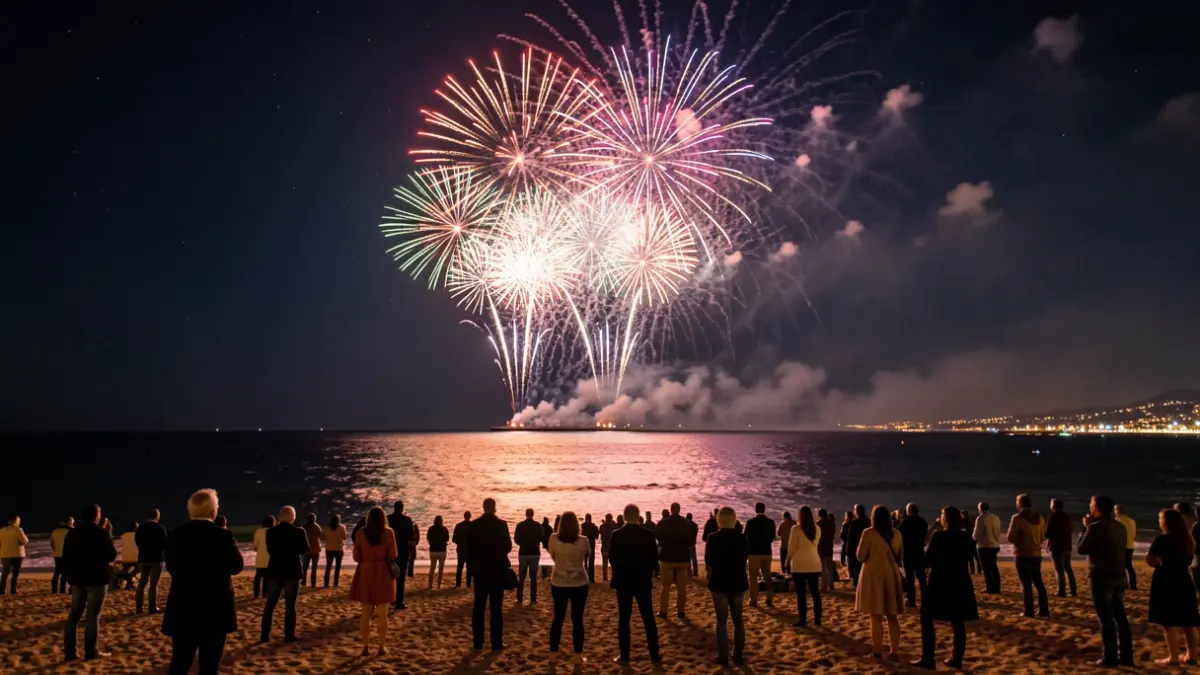 Night fireworks display over the sea in Blanes, with people watching from the beach.