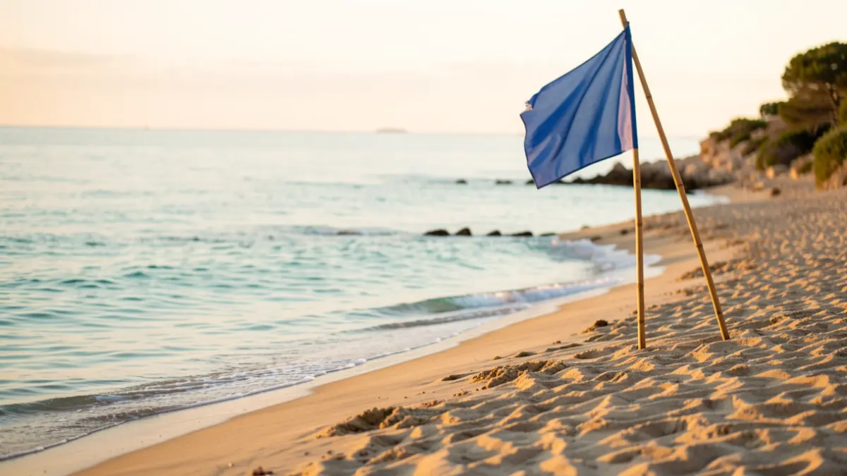 Generic image of a Mediterranean beach with a blue flag in the background.