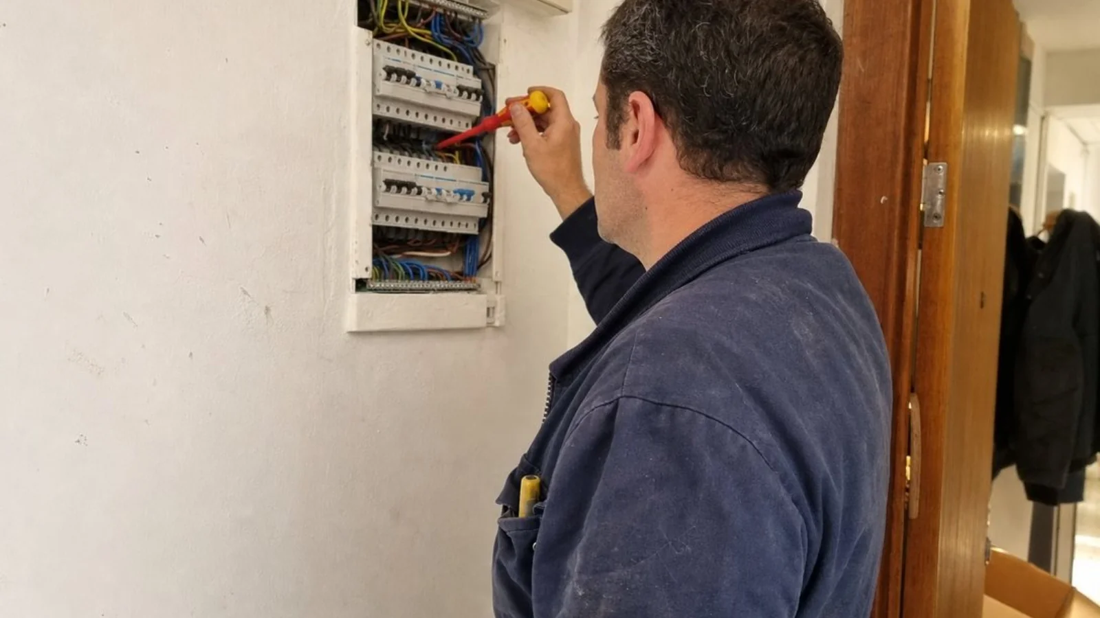 Electrician working on a European electrical panel inside a home