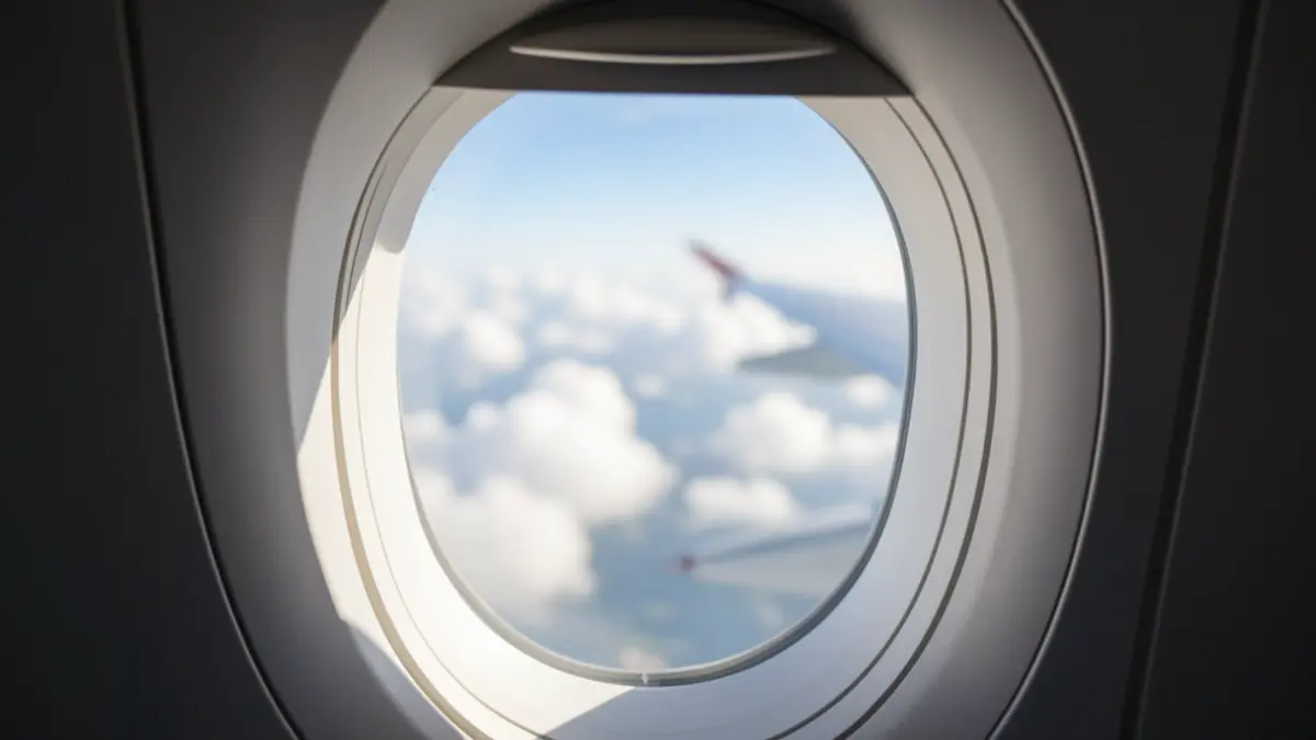 Airplane window with a view of the sky.