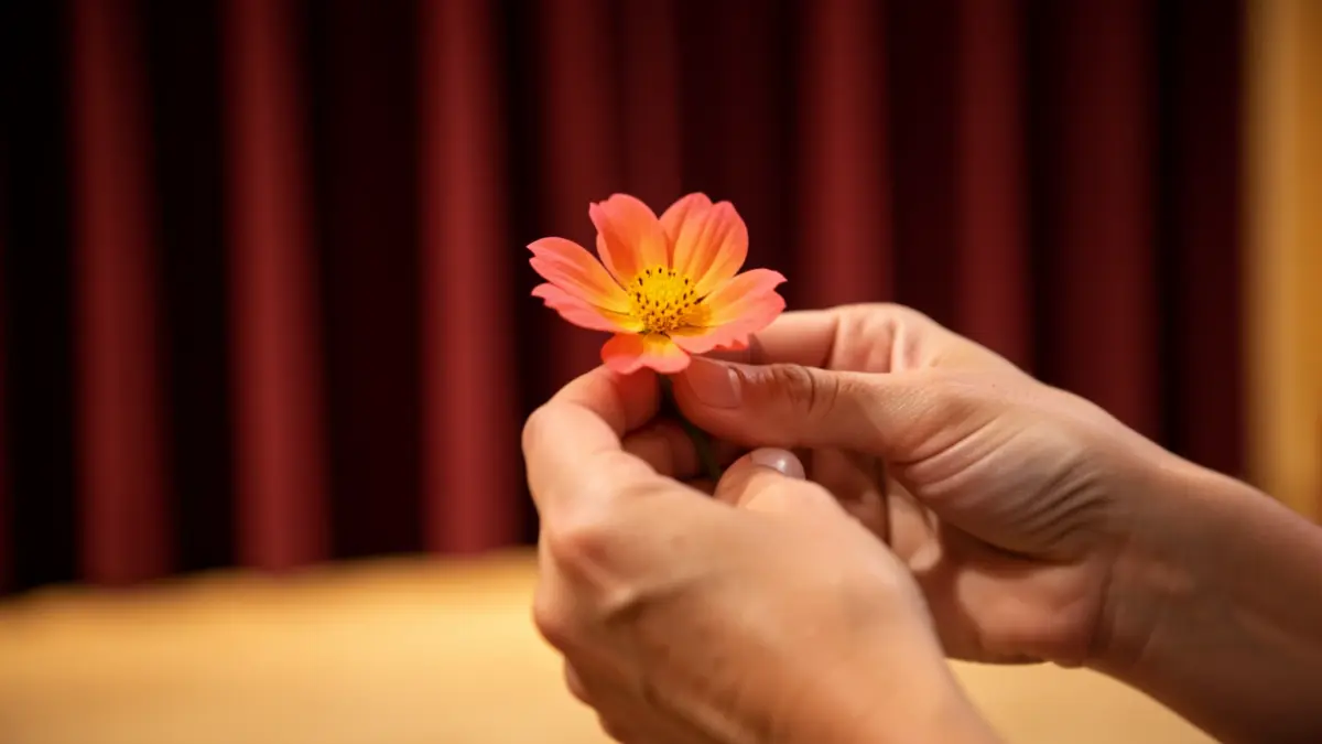 Mujer con una flor delante de un telón de teatro.