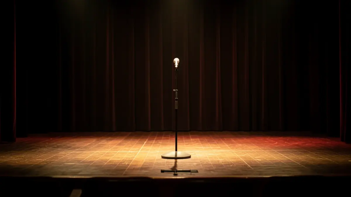 Empty theatre stage with a microphone lit by spotlights.