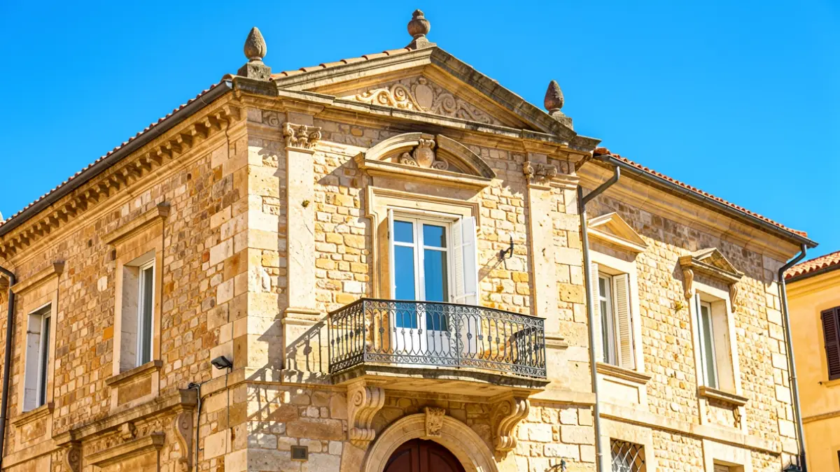 Generic image of a stone town hall facade with a balcony and blue sky.