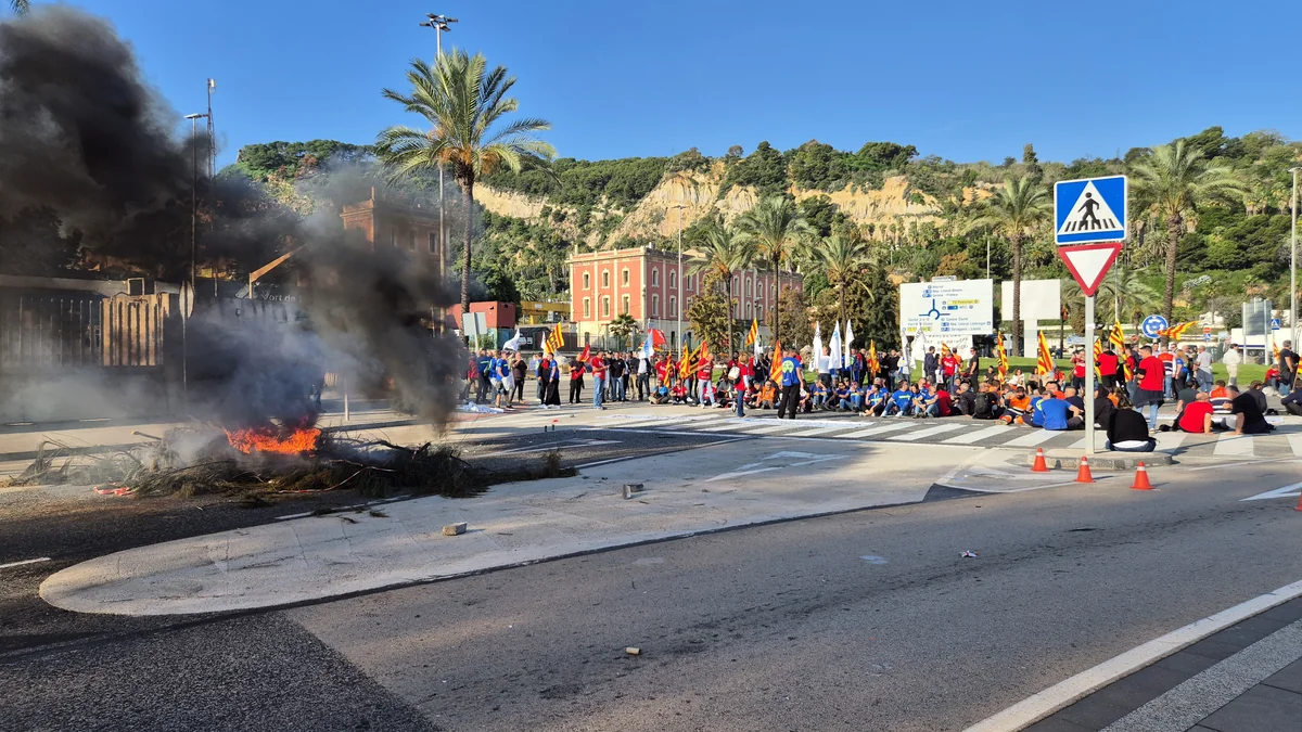 Treballadors de l'Autoritat Portuària de Barcelona concentrats en una rotonda del port, al costat d'una foguera, durant la protesta d'aquest dimecres.